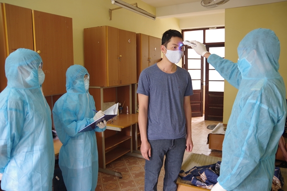Cán bộ, nhân viên Ban CHQS quận Lê Chân kiểm tra thân nhiệt các công dân trong khu cách ly tại ký túc xá Trường Đại học Quản lý và Công nghệ Hải Phòng.